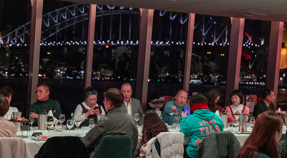 Guests dining on the Clearview with a view of the Harbour Bridge behind them