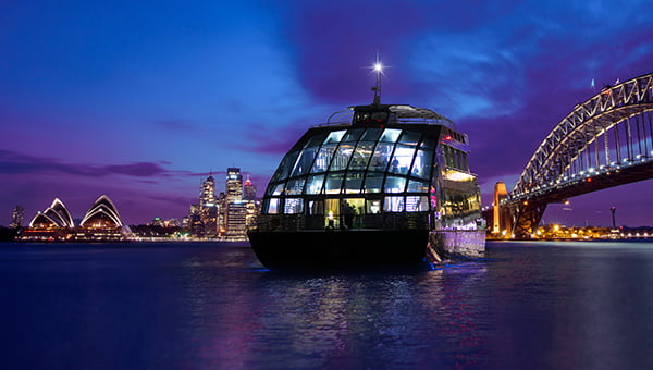 A premium glass boat cruises the harbour attractions and the city skyline on the serene blue waters.