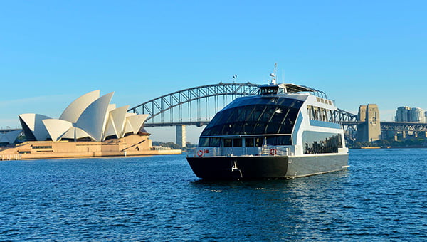 The premium glass boat cruises past the iconic attractions on the waters under the blue sky.