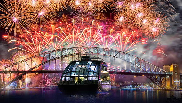 A luxury glass boat cruises past the fireworks over the Harbour Bridge